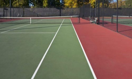 A green, red and white Tennis court with a tennis net going through the middle of the court painted by a line painter in Cambridge